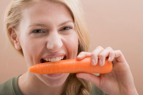 Девушка грызет морковь